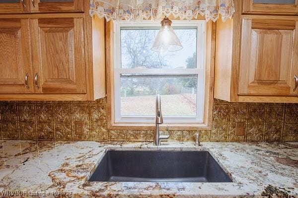 room details featuring tasteful backsplash, light stone countertops, and sink