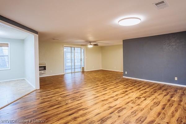 empty room featuring heating unit, ceiling fan, and wood-type flooring