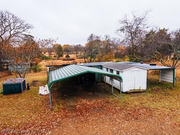 back of house with a carport and a storage unit