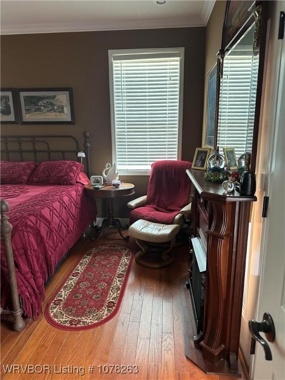 bedroom with ornamental molding, hardwood / wood-style floors, and multiple windows