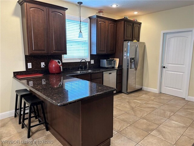 21 Bermuda Ct, Mountain Home, AR 72653 - kitchen featuring stainless steel appliances, a sink, dark brown cabinetry, backsplash, and a peninsula