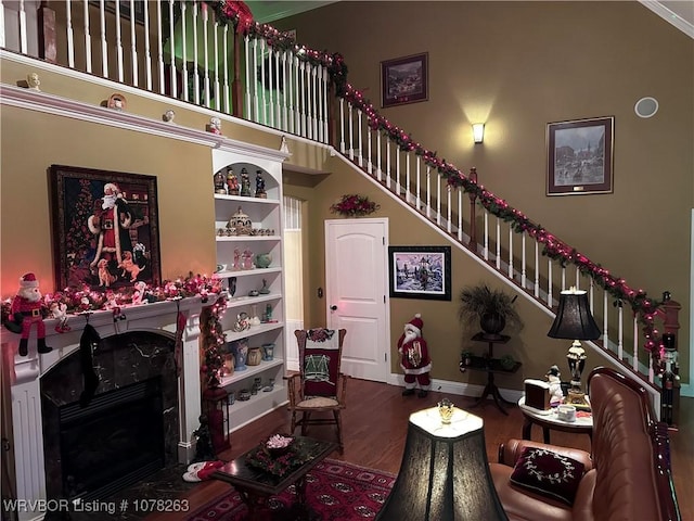 living room with a high end fireplace, crown molding, dark hardwood / wood-style flooring, a high ceiling, and built in features