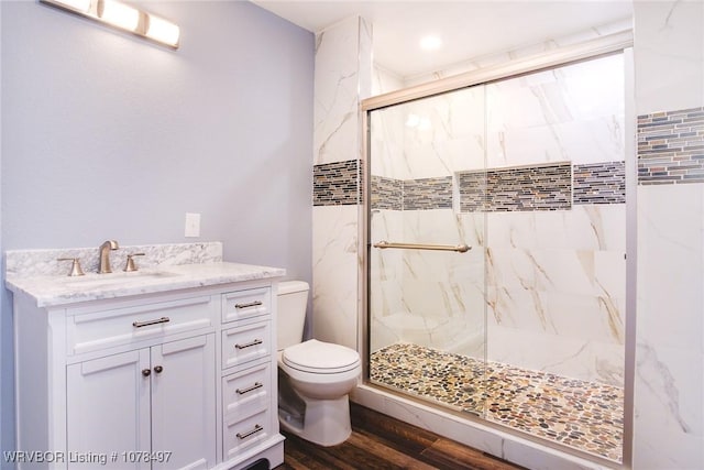 bathroom with a shower with door, vanity, hardwood / wood-style floors, and toilet