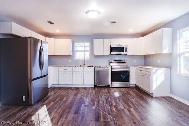 kitchen featuring stainless steel appliances, white cabinetry, and dark hardwood / wood-style flooring