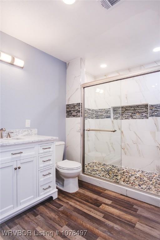 bathroom featuring hardwood / wood-style flooring, vanity, toilet, and a shower with door