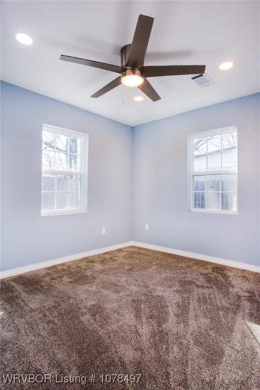 carpeted spare room featuring a healthy amount of sunlight and ceiling fan