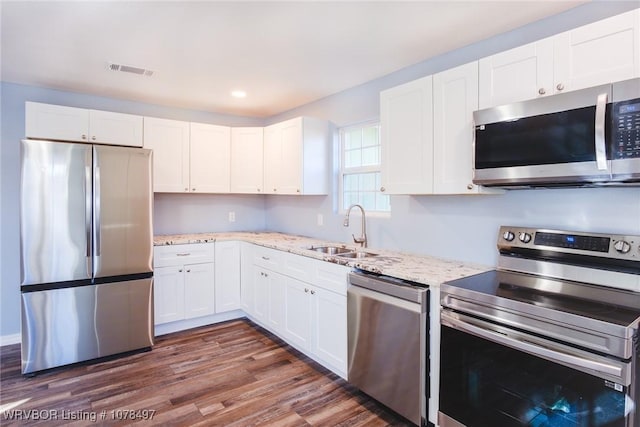 kitchen with stainless steel appliances, white cabinetry, sink, and dark wood-type flooring