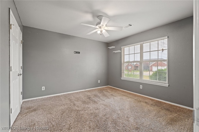 carpeted empty room featuring a ceiling fan and baseboards