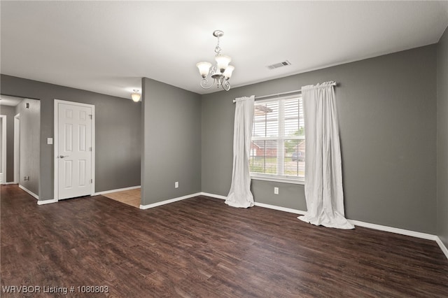 spare room featuring a chandelier, wood finished floors, and baseboards