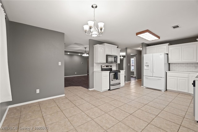 kitchen with stainless steel range with electric cooktop, white refrigerator with ice dispenser, black microwave, a chandelier, and backsplash
