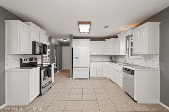 kitchen featuring appliances with stainless steel finishes, a sink, backsplash, white cabinets, and light tile patterned floors