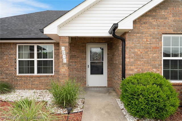 property entrance with brick siding and a shingled roof