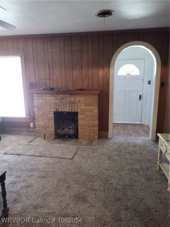 122 N Logan St, Charleston, AR 72933 - unfurnished living room with arched walkways, a brick fireplace, carpet, and wooden walls
