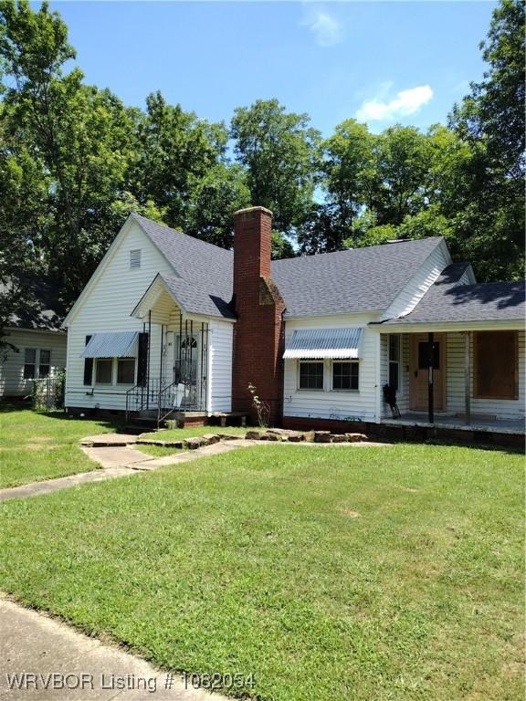 122 N Logan St, Charleston, AR 72933 - view of front of house featuring a front yard, a chimney, a shingled roof, and covered porch