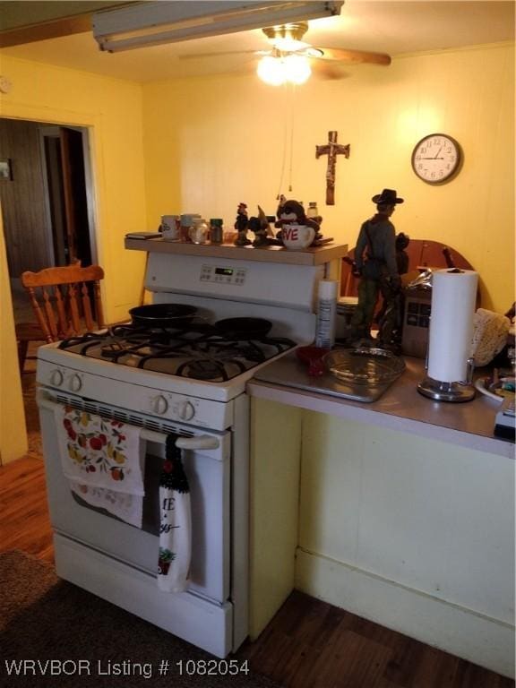 122 N Logan St, Charleston, AR 72933 - kitchen featuring white range with gas cooktop, a ceiling fan, and dark wood-style floors