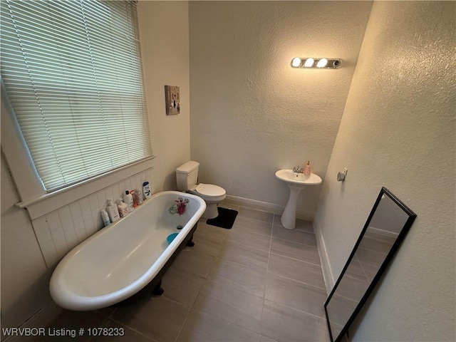 bathroom featuring tile patterned floors, toilet, and a bath