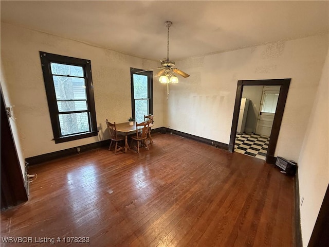 unfurnished dining area with ceiling fan and dark wood-type flooring