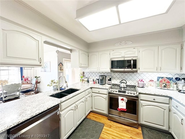 kitchen featuring white cabinetry, sink, backsplash, appliances with stainless steel finishes, and light wood-type flooring