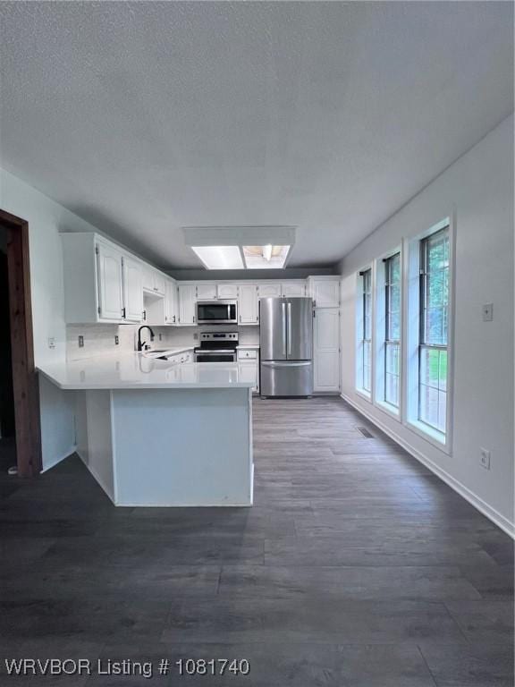 2015 Woodwind Way, Van Buren, AR 72956 - kitchen with stainless steel appliances, a peninsula, light countertops, white cabinets, and a skylight