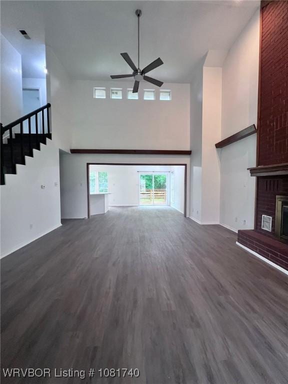 2015 Woodwind Way, Van Buren, AR 72956 - unfurnished living room featuring a high ceiling, a brick fireplace, a ceiling fan, stairs, and dark wood-style floors