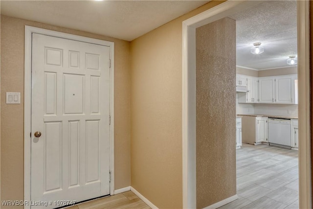 hall with a textured ceiling and light wood-type flooring