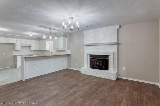 unfurnished living room featuring dark wood-type flooring, a chandelier, and a textured ceiling