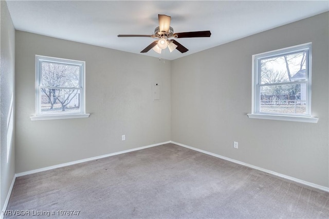 carpeted spare room featuring a wealth of natural light and ceiling fan