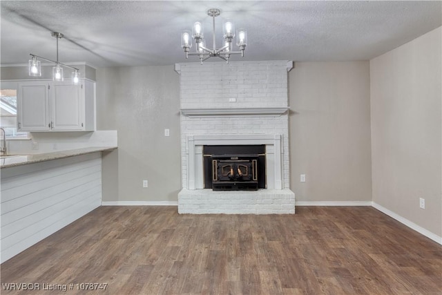 unfurnished living room featuring dark hardwood / wood-style floors, sink, a notable chandelier, and a textured ceiling