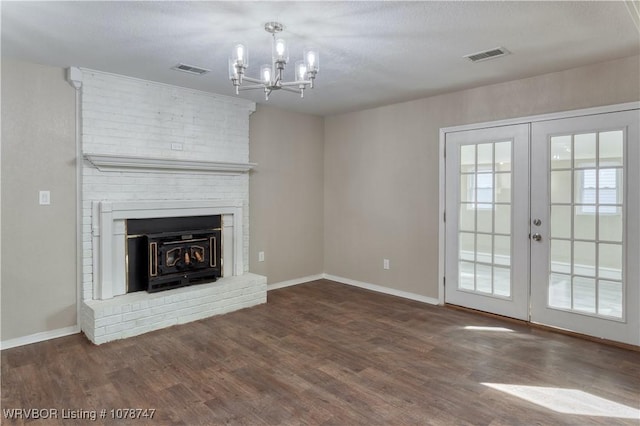 unfurnished living room with a textured ceiling, dark wood-type flooring, french doors, and a chandelier