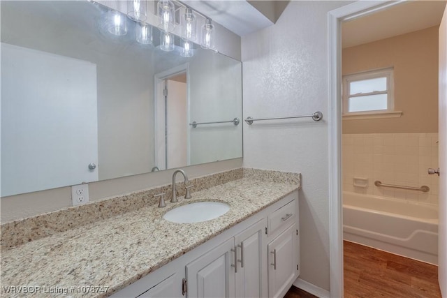 bathroom with hardwood / wood-style flooring, vanity, and a washtub