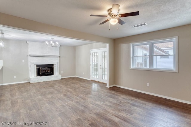 unfurnished living room featuring french doors, wood-type flooring, a textured ceiling, ceiling fan, and a fireplace