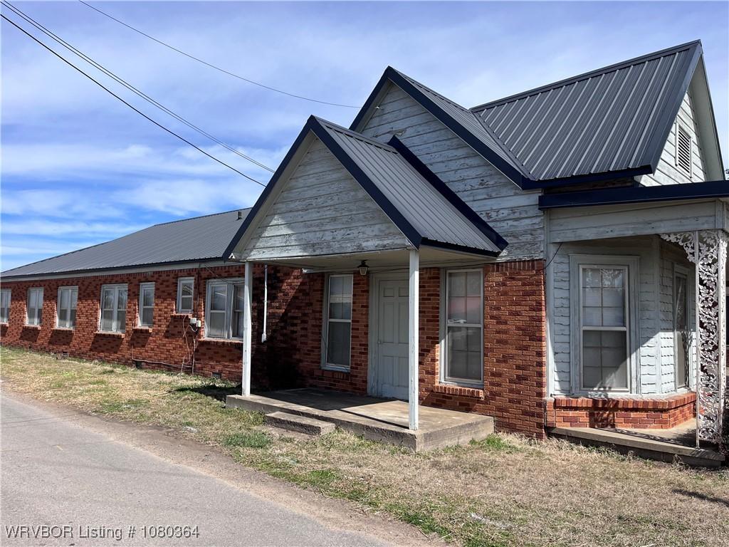 72 2nd St, Waldron, AR 72958 - view of side of property featuring brick siding and metal roof