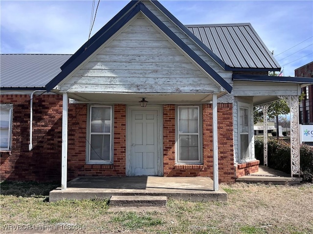 72 2nd St, Waldron, AR 72958 - view of front of property with brick siding, a porch, and metal roof