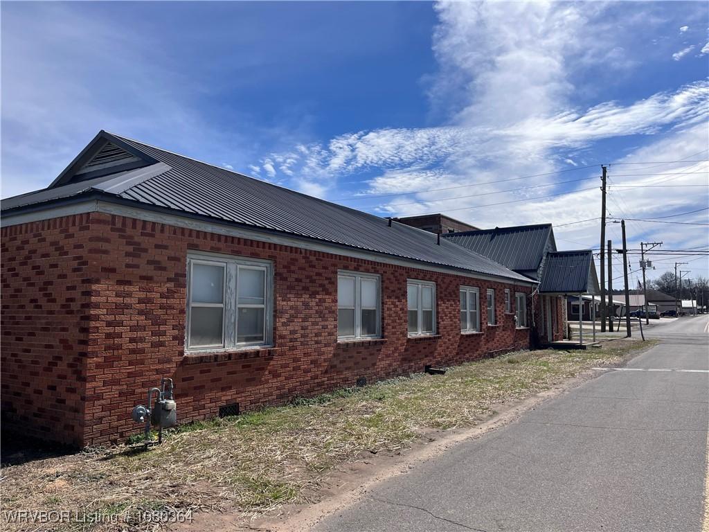 72 2nd St, Waldron, AR 72958 - view of home's exterior featuring brick siding and metal roof