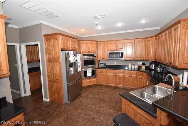kitchen with stainless steel appliances, a sink, dark countertops, ornamental molding, and dark tile patterned floors