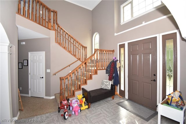 carpeted entryway with a towering ceiling, stairway, and baseboards