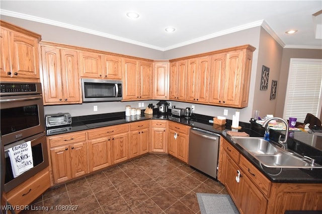kitchen with appliances with stainless steel finishes, a sink, dark countertops, a peninsula, and crown molding