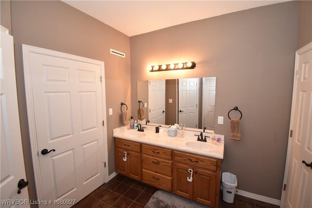 full bath featuring tile patterned floors, double vanity, and baseboards