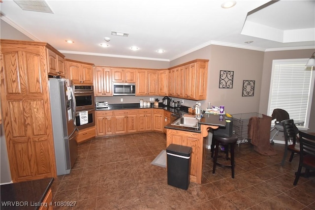 kitchen with stainless steel appliances, a sink, a peninsula, a kitchen bar, and dark tile patterned flooring