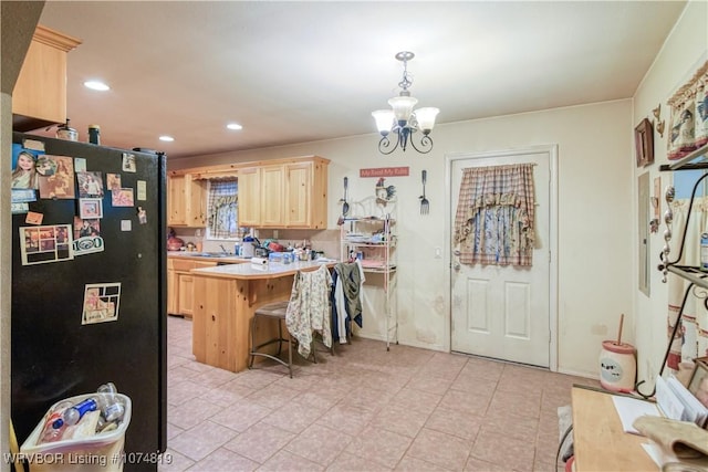 kitchen with black refrigerator, light brown cabinetry, kitchen peninsula, pendant lighting, and a breakfast bar area