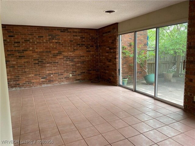 1500 S Albert Pike Ave Unit 40, Fort Smith, AR 72903 - spare room featuring brick wall, a textured ceiling, and light tile patterned flooring