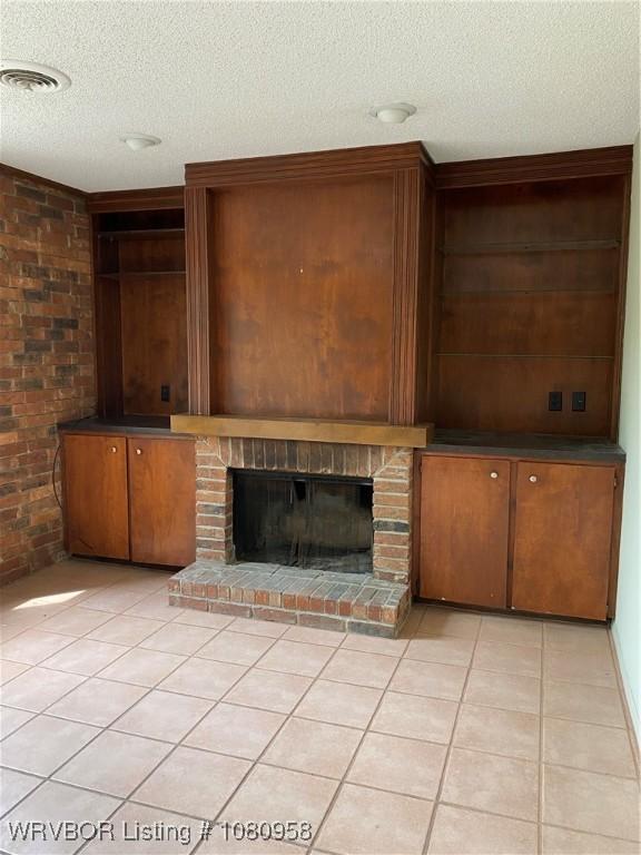 1500 S Albert Pike Ave Unit 40, Fort Smith, AR 72903 - unfurnished living room featuring a textured ceiling, light tile patterned floors, a brick fireplace, and brick wall