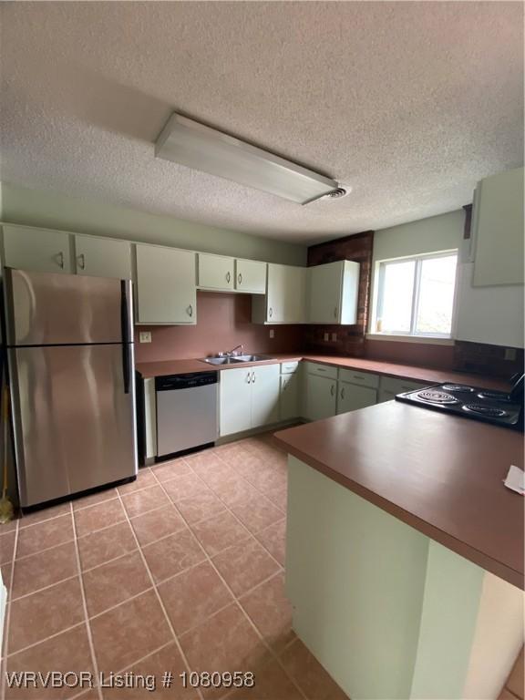 1500 S Albert Pike Ave Unit 40, Fort Smith, AR 72903 - kitchen featuring stainless steel appliances, a textured ceiling, light tile patterned flooring, dark countertops, and a sink