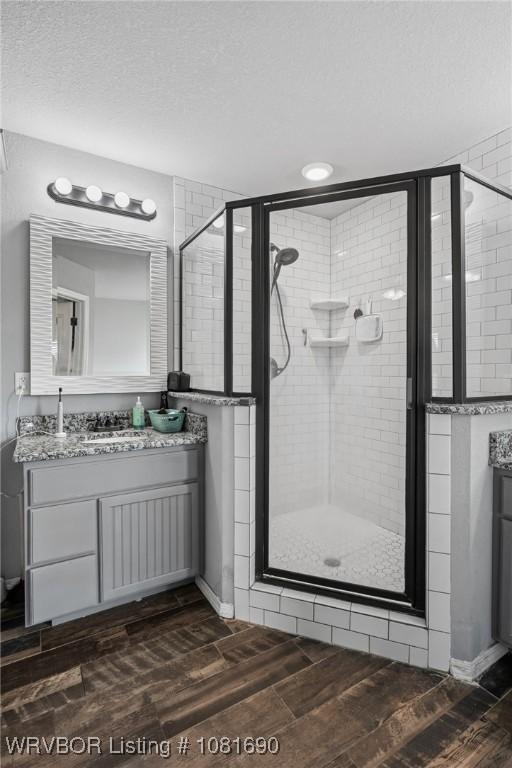 2207 Lisa Ln, Van Buren, AR 72956 - bathroom with vanity, wood finished floors, a stall shower, a textured ceiling, and recessed lighting