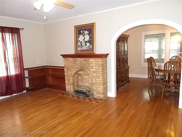 619 N 40th St, Fort Smith, AR 72903 - living room featuring a fireplace, arched walkways, ceiling fan, wood finished floors, and ornamental molding