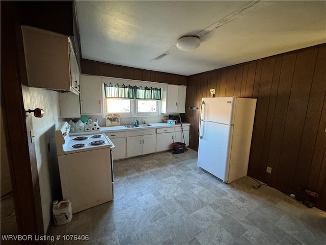 kitchen featuring sink, white fridge, wooden walls, white cabinets, and range