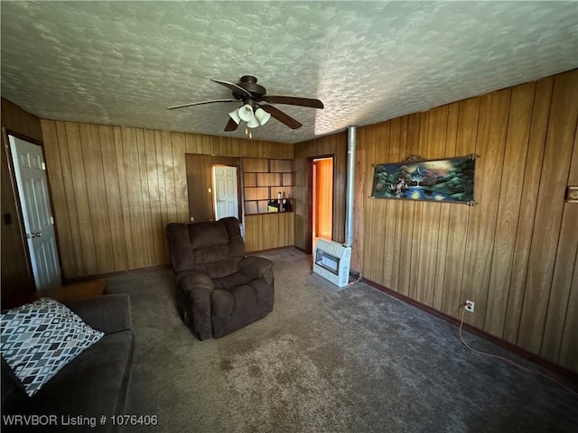 carpeted living room with heating unit, ceiling fan, wood walls, and a textured ceiling