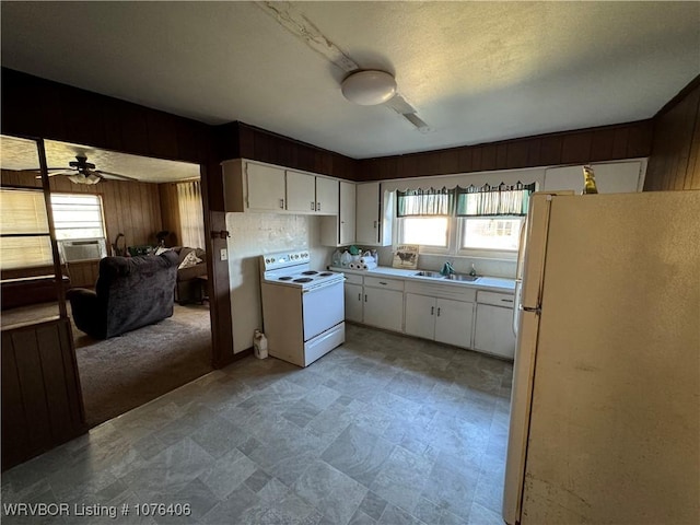 kitchen featuring wood walls, sink, white cabinets, and white appliances