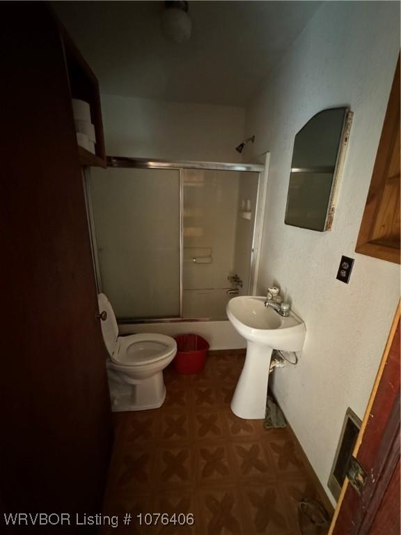 bathroom featuring shower / bath combination with glass door and toilet