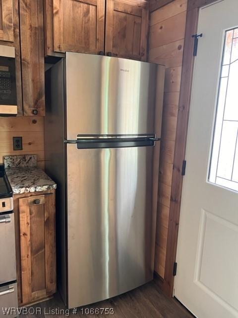 kitchen featuring a healthy amount of sunlight, wood walls, and stainless steel appliances